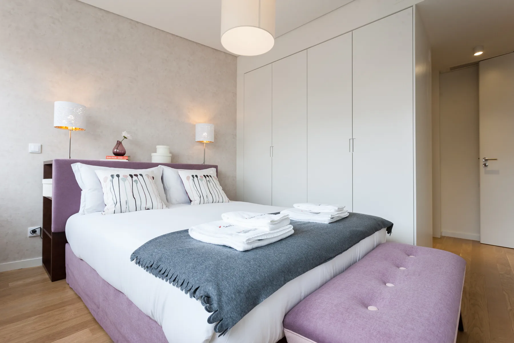 Dormitorio con una cama bien tendida y armarios blancos.