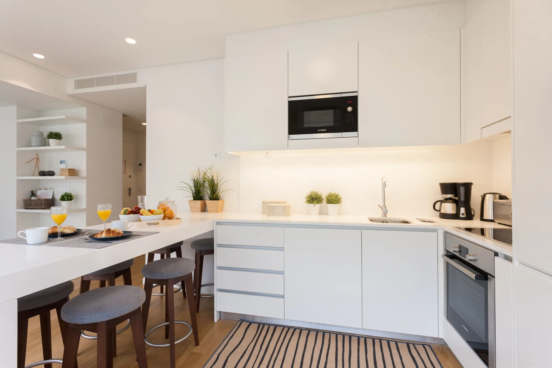 Una cocina luminosa con una barra para comer y electrodomésticos integrados.