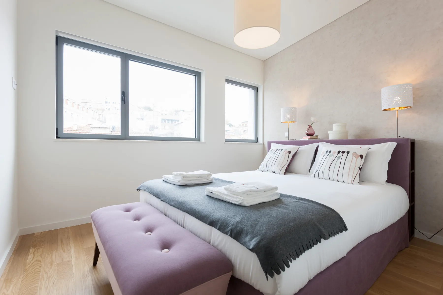 Un dormitorio luminoso con una cama bien tendida y ventanas amplias.