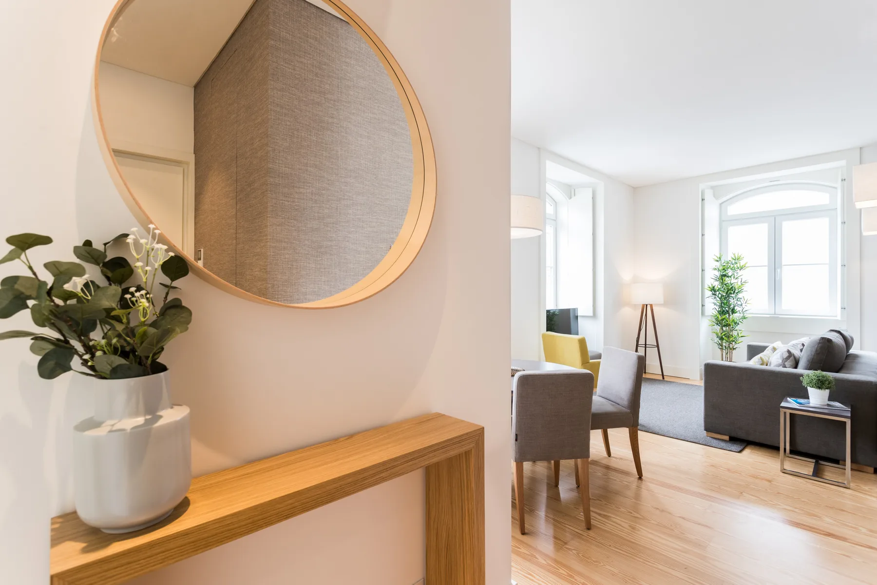 A bright living room with seating, large windows, and a wooden console table.