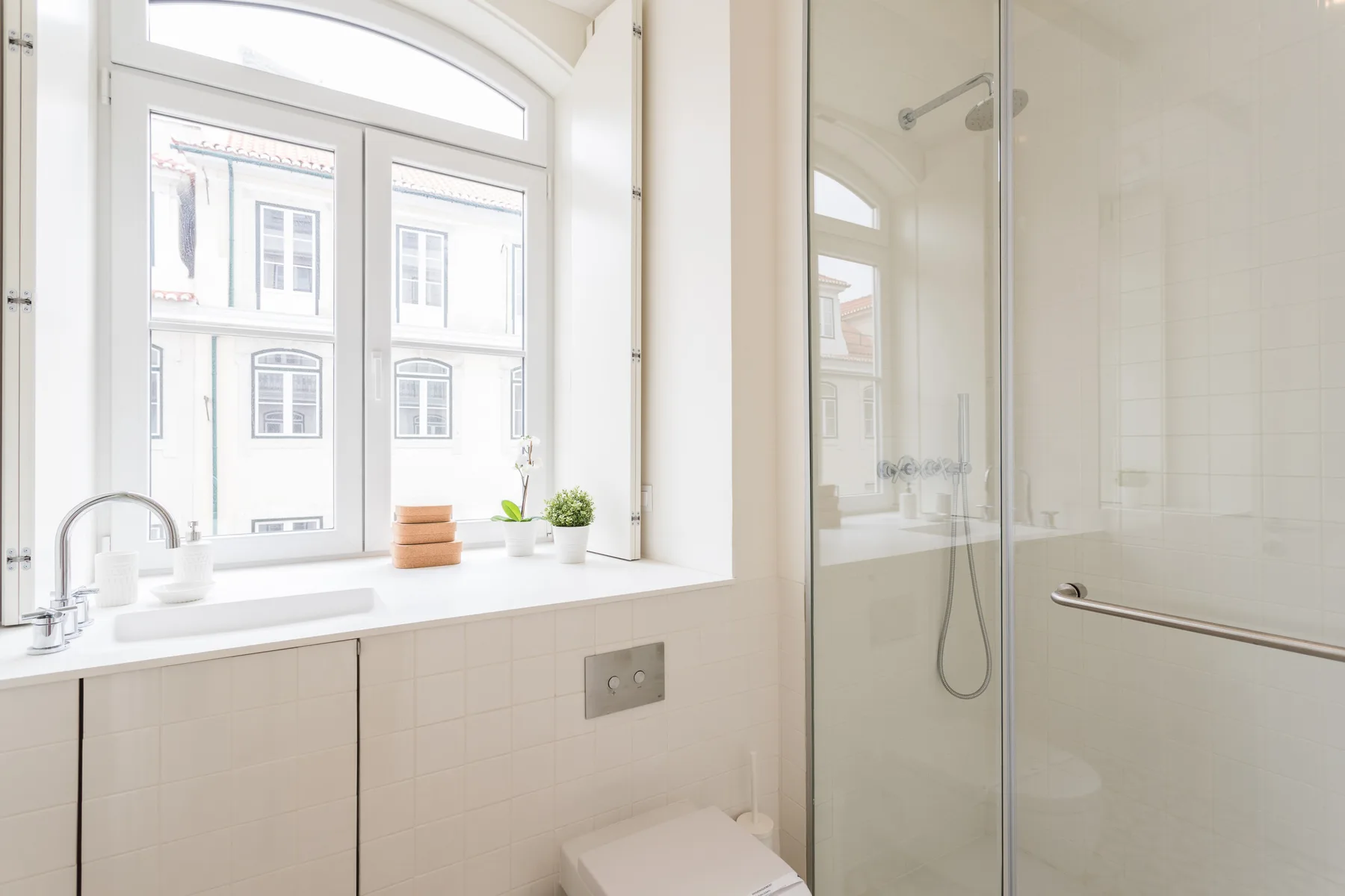 A bright bathroom with a large window beside the shower.