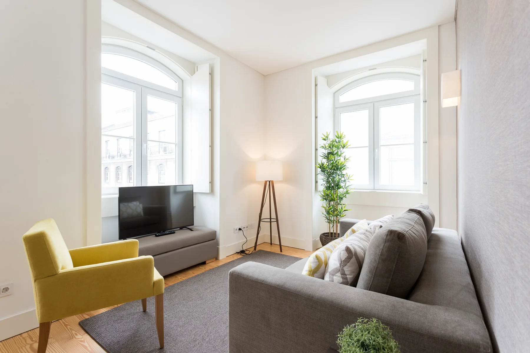 A bright living room with seating, a television, and large windows.