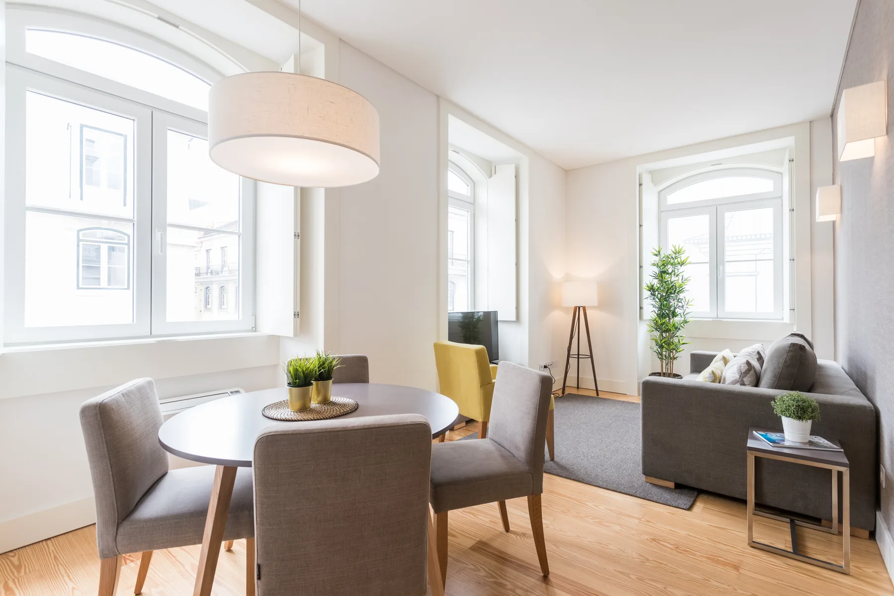 A bright living and dining area with large windows and seating.