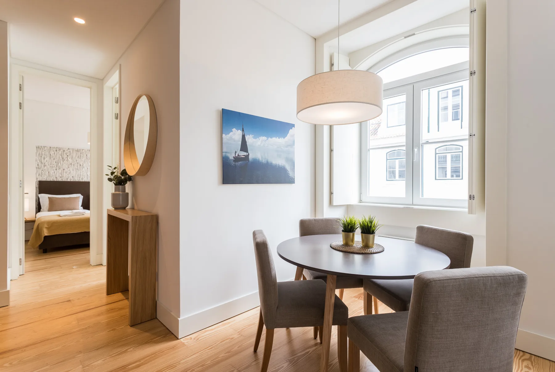 A dining area with a round table and chairs beside a large window.