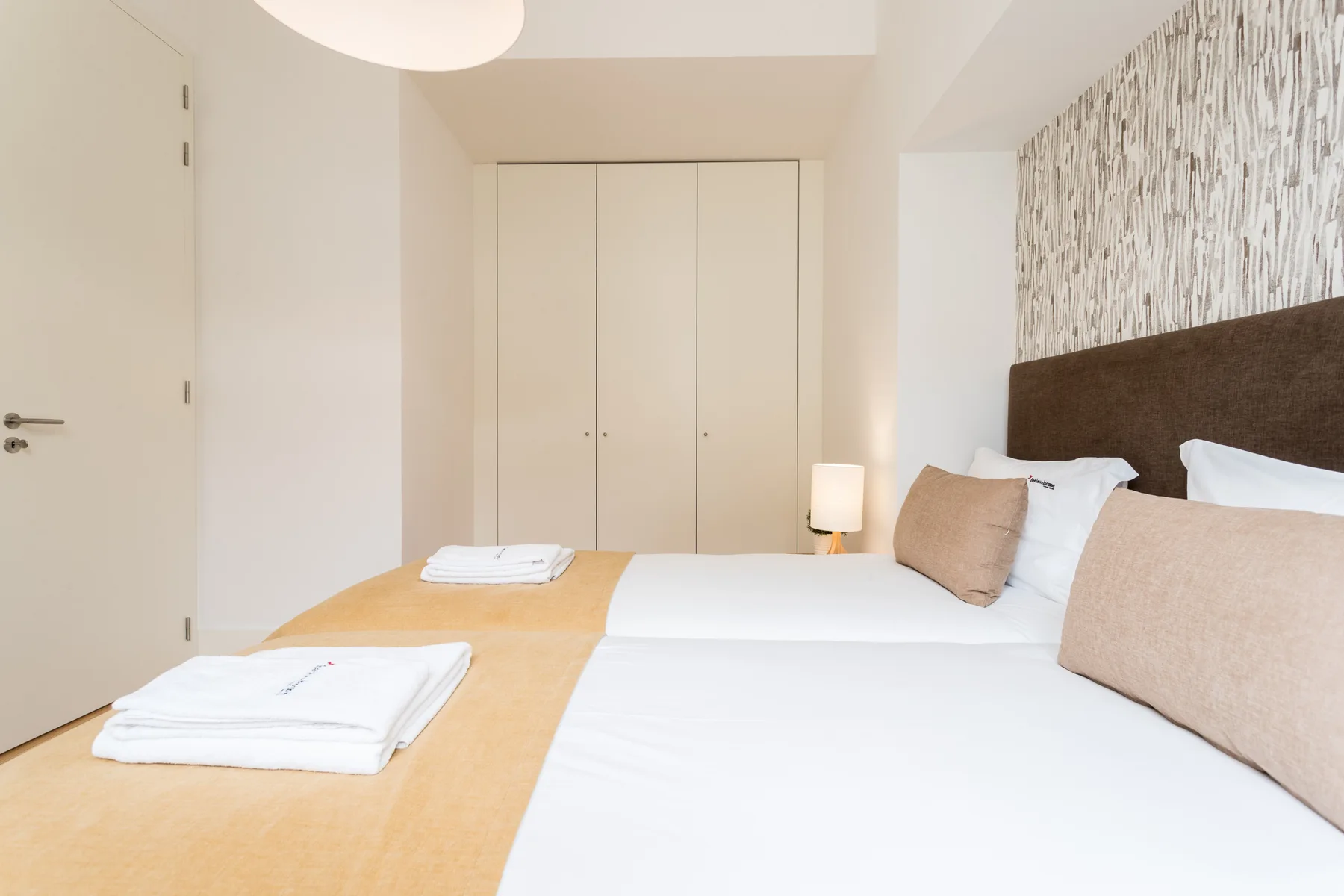 A bedroom with a bed, folded towels, and a wardrobe.