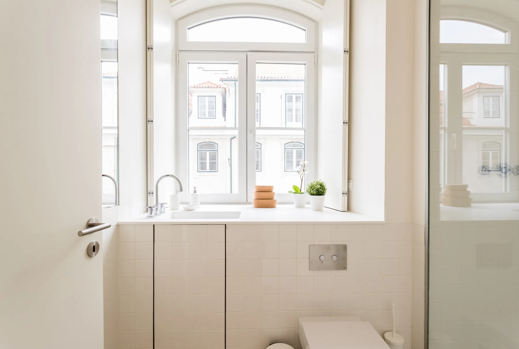 A bright bathroom with a window above the sink and toilet.