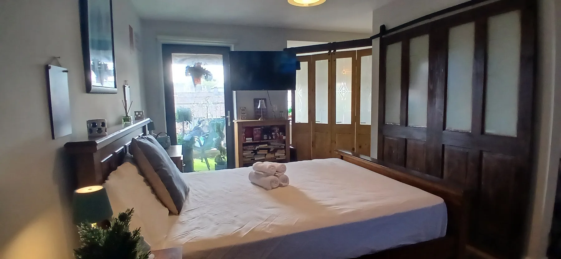 A bedroom with a neatly made bed and wooden doors.