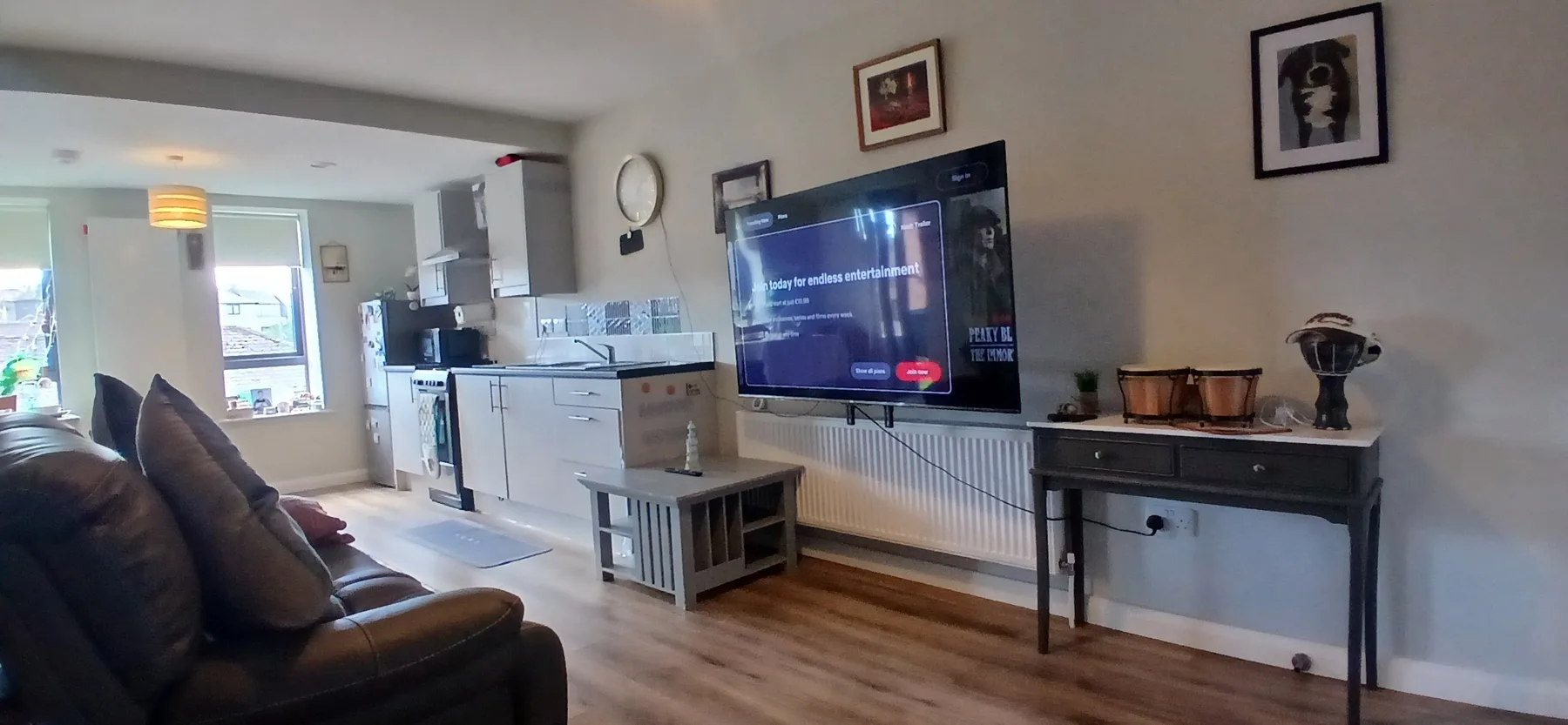 A living room with seating, a television, and a dining area in the background.