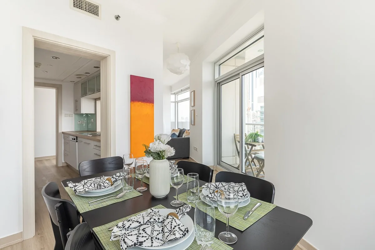 Comedor con la mesa puesta junto a una luminosa puerta corrediza de vidrio.
