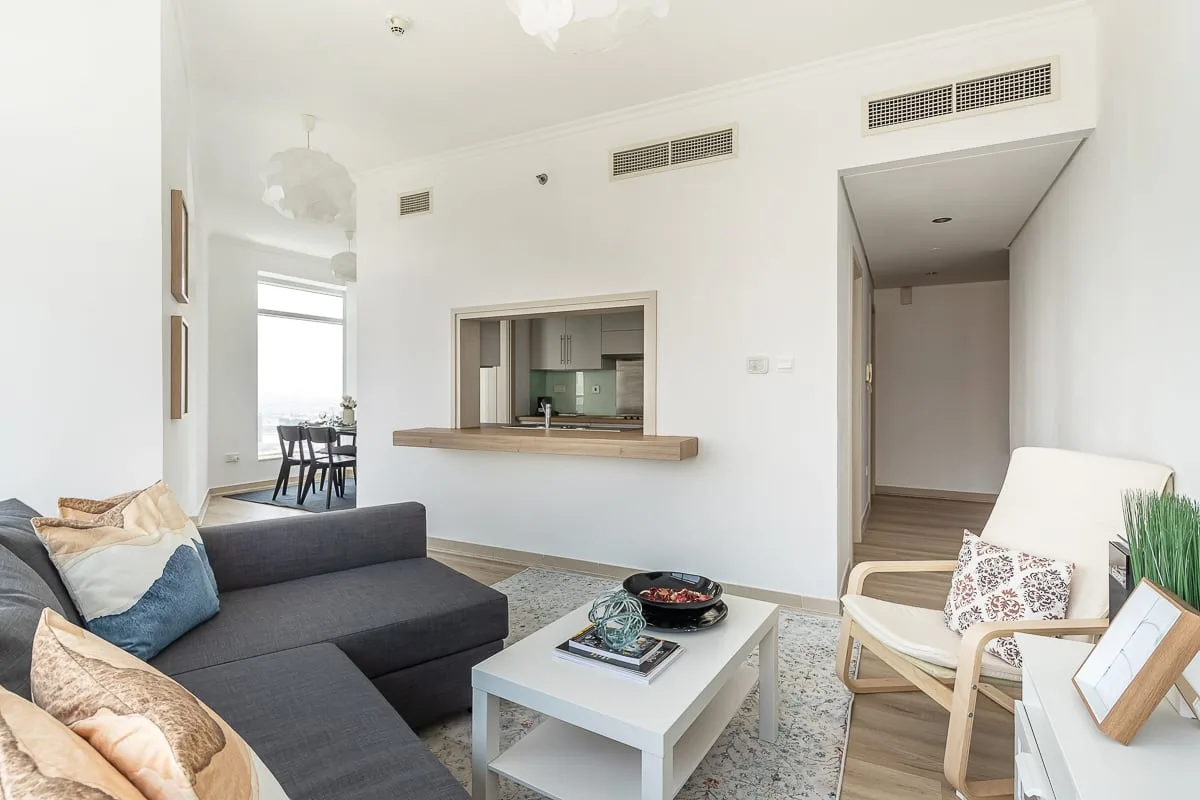 Una sala luminosa con asientos, una mesa de centro y una barra hacia la cocina.