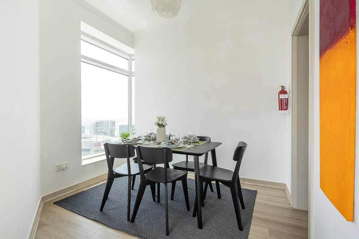Un comedor con la mesa puesta junto a una ventana grande.