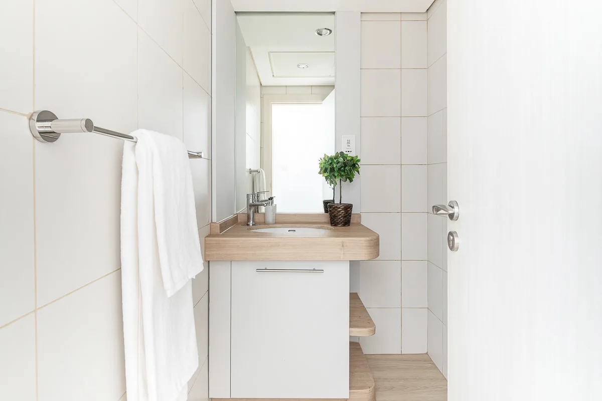 Un baño luminoso con azulejos, lavabo, espejo y toalla blanca.
