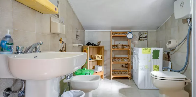 Un baño compacto con lavabo, inodoro y estantes de almacenamiento bajo un techo inclinado.