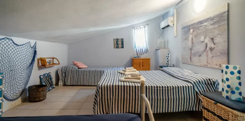 Un dormitorio con camas a rayas, una cómoda pequeña y arte en la pared.