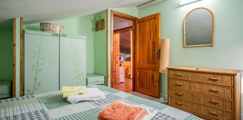 Un dormitorio con una cama, un armario y una cómoda de madera.