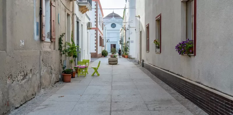 Una calle peatonal estrecha pasa entre edificios y llega hasta una pequeña iglesia.