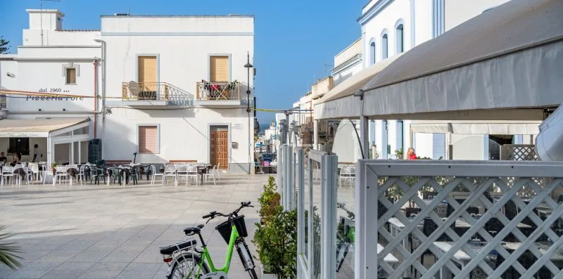 Una zona exterior pavimentada con mesas junto a edificios blancos.