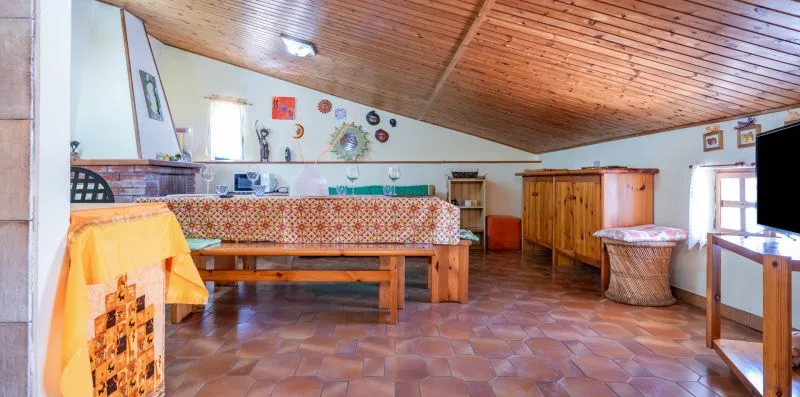 A rustic dining area with a long wooden table beneath a sloped wood ceiling.