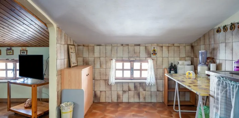 Una zona de cocina con azulejos, una encimera y una ventana con cortinas.