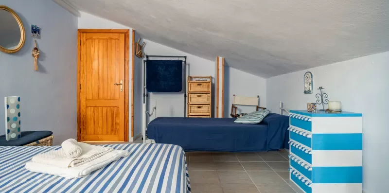 Un dormitorio con dos camas y una cómoda a rayas azules y blancas.