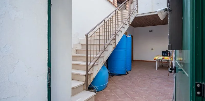 Una escalera interior con barandillas metálicas pasa junto a tanques de agua azules.