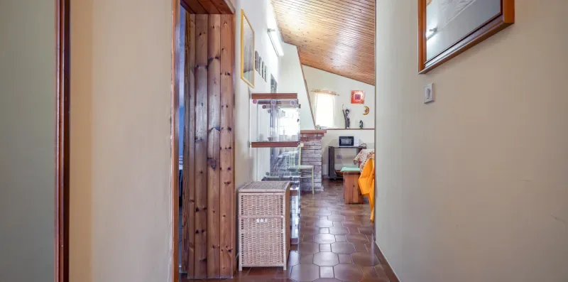 Un pasillo con suelo de baldosas conduce a un comedor bajo un techo inclinado de madera.