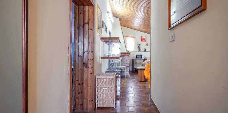 A hallway opens into a dining area with a tiled floor and wooden ceiling.