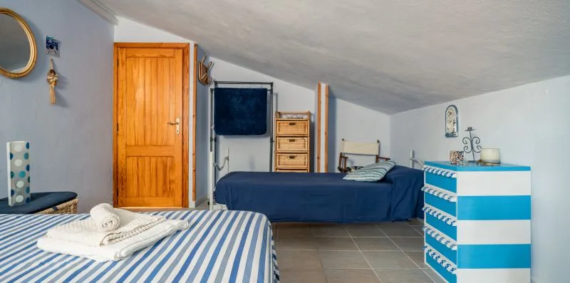 Un dormitorio con camas, una puerta de madera y una cómoda azul y blanca.