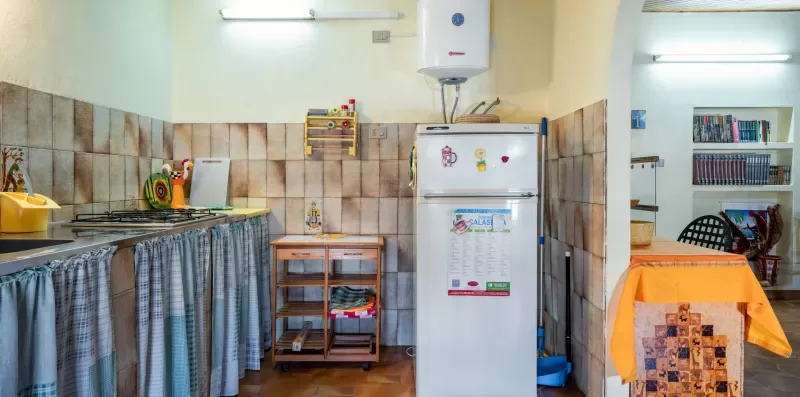 Una zona de cocina alicatada con encimera, refrigerador y una mesa pequeña.
