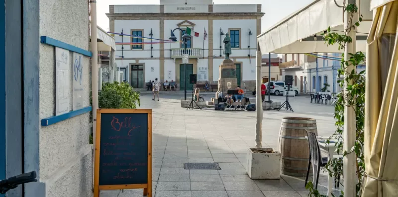 Una plaza pavimentada con asientos al aire libre y un edificio al otro lado.