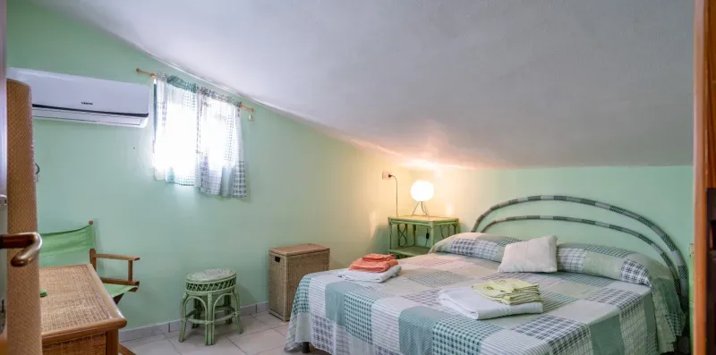 Un dormitorio con una cama estampada y una mesita al lado.