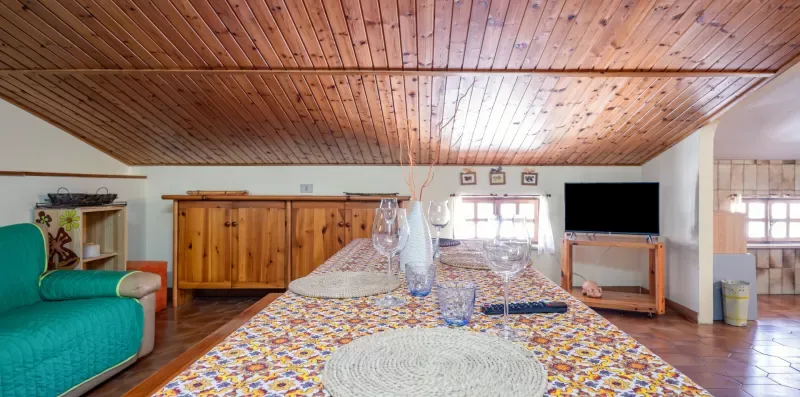 Una sala de estar con una mesa cubierta con un mantel colorido y un armario de madera.