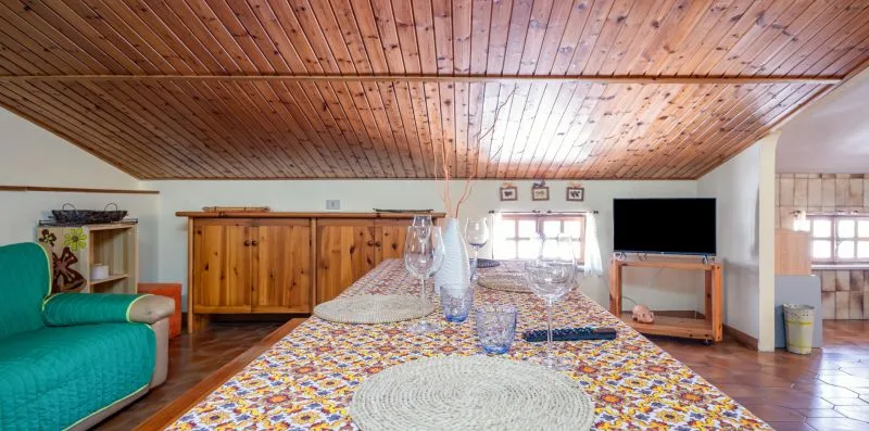 Una mesa de comedor con un mantel colorido está bajo un techo de madera.