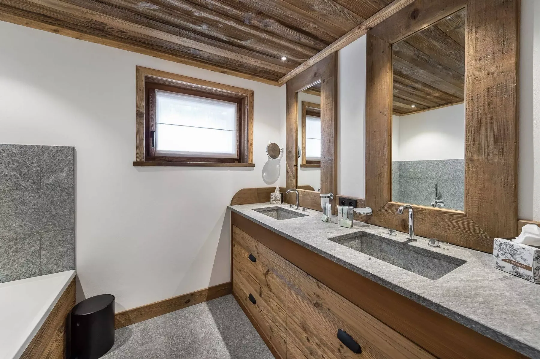 A bathroom vanity with two sinks sits beneath large mirrors and a wood-plank ceiling.