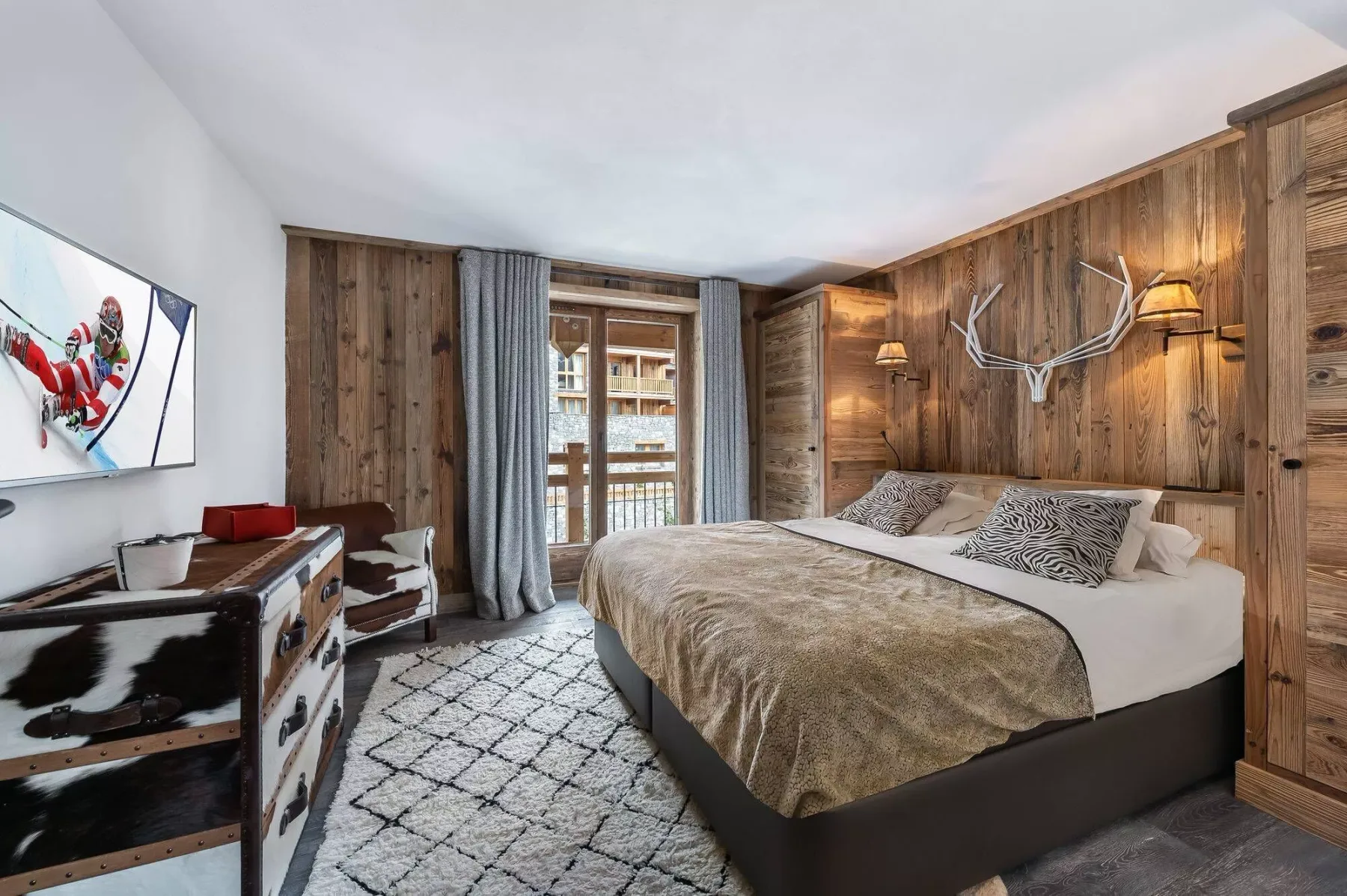 A bedroom with a large bed, wood-paneled walls, and a patterned rug.