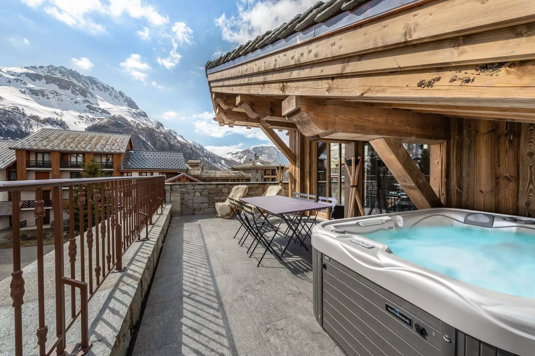 A mountain-view terrace with an outdoor hot tub and patio seating.