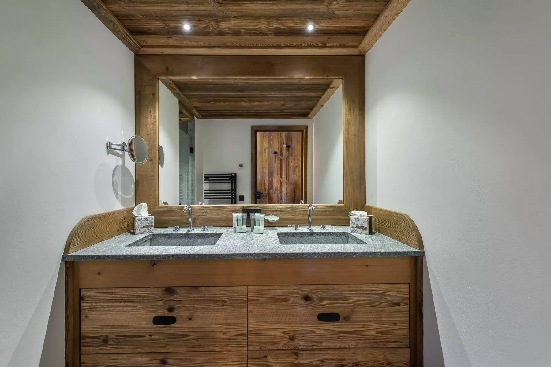 A bathroom vanity with a wide mirror and two sinks.