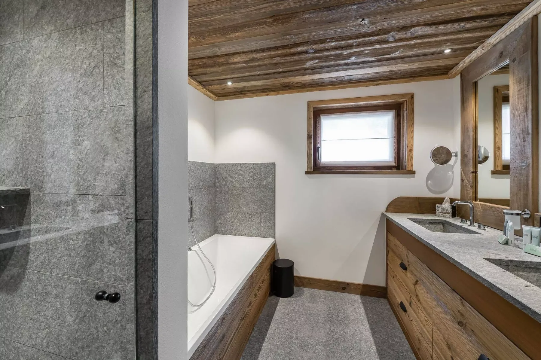 A bathroom with a bathtub, glass shower, and long vanity.