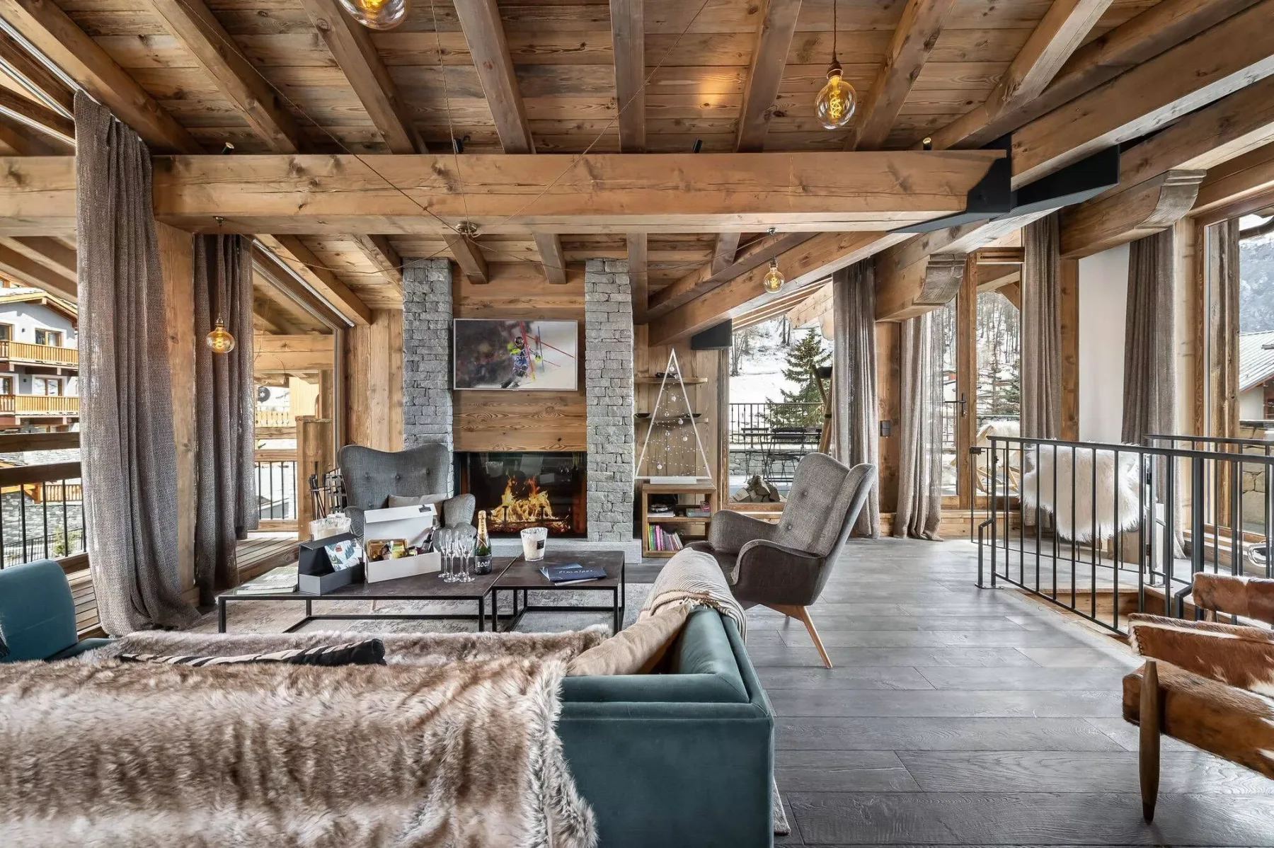 A living room with a stone fireplace and seating beneath exposed wooden beams.