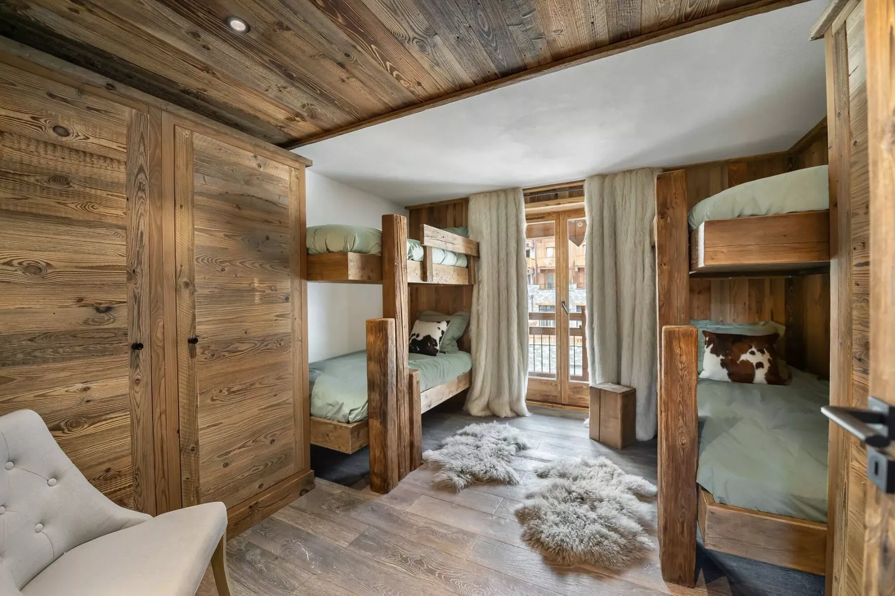 A wood-paneled bedroom with bunk beds and a curtained glass door.