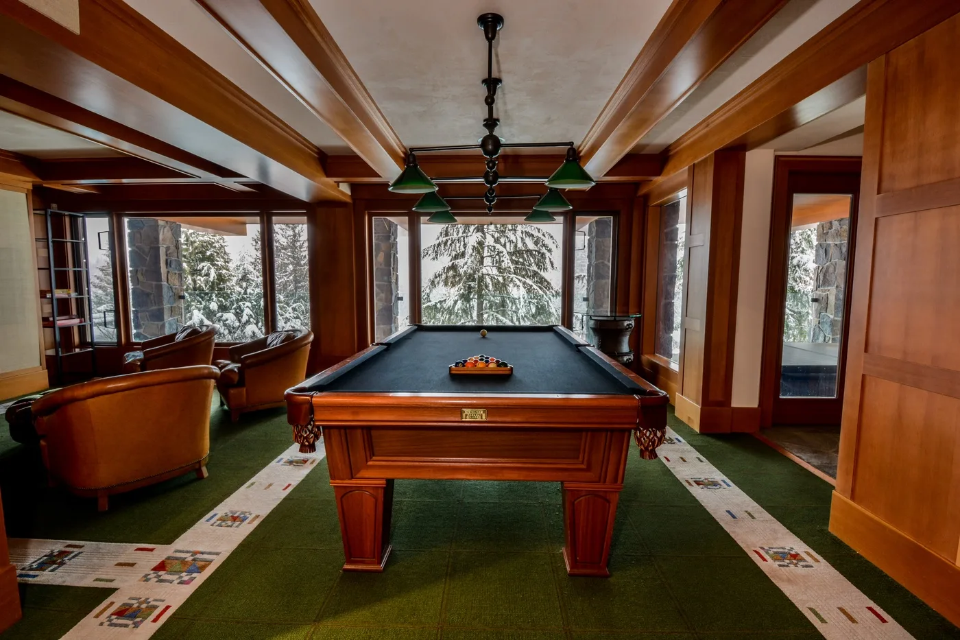 A billiards room with a pool table and seating by the windows.