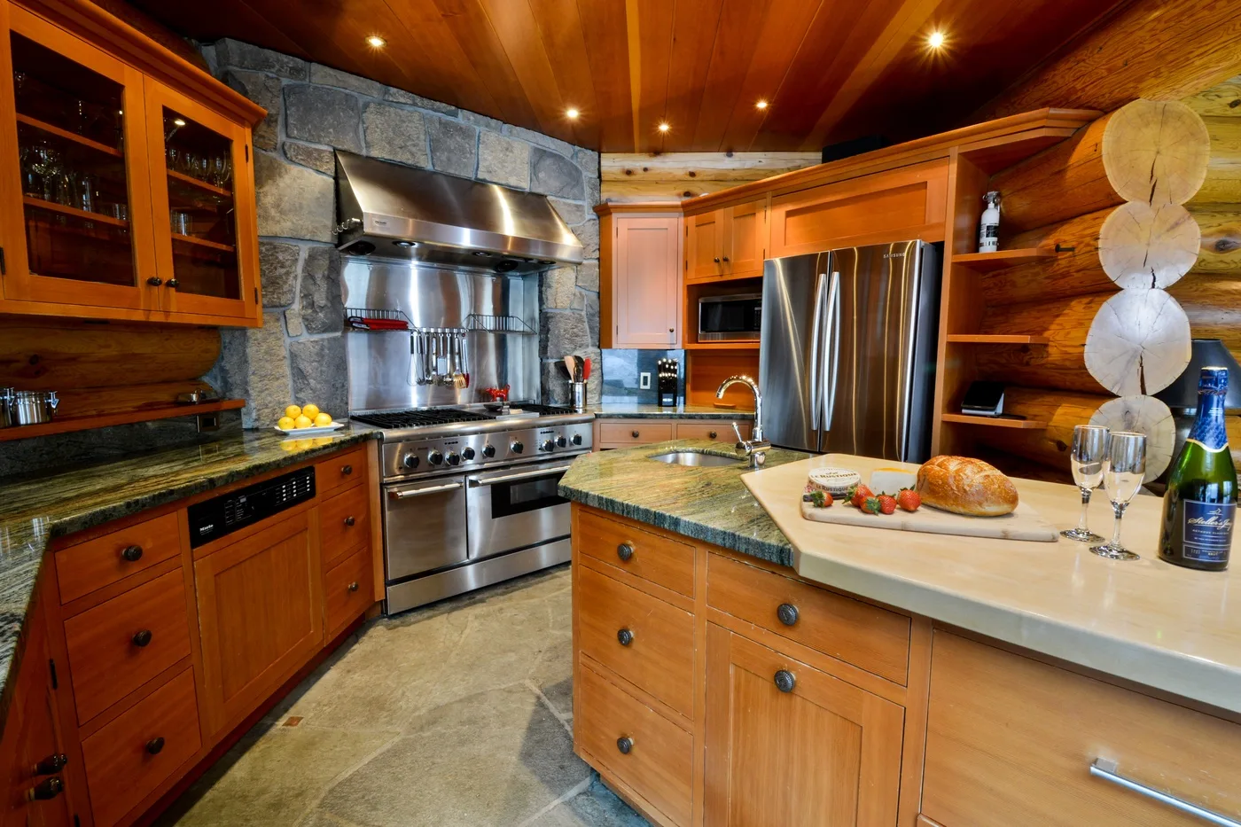 Una cocina con gabinetes de madera, paredes de piedra y una gran isla central.