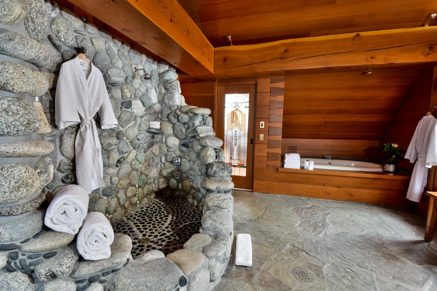 A wood-paneled room with a stone soaking tub and folded towels.
