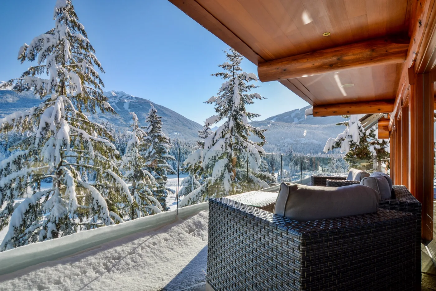 A covered outdoor seating area overlooks a snowy mountain landscape.