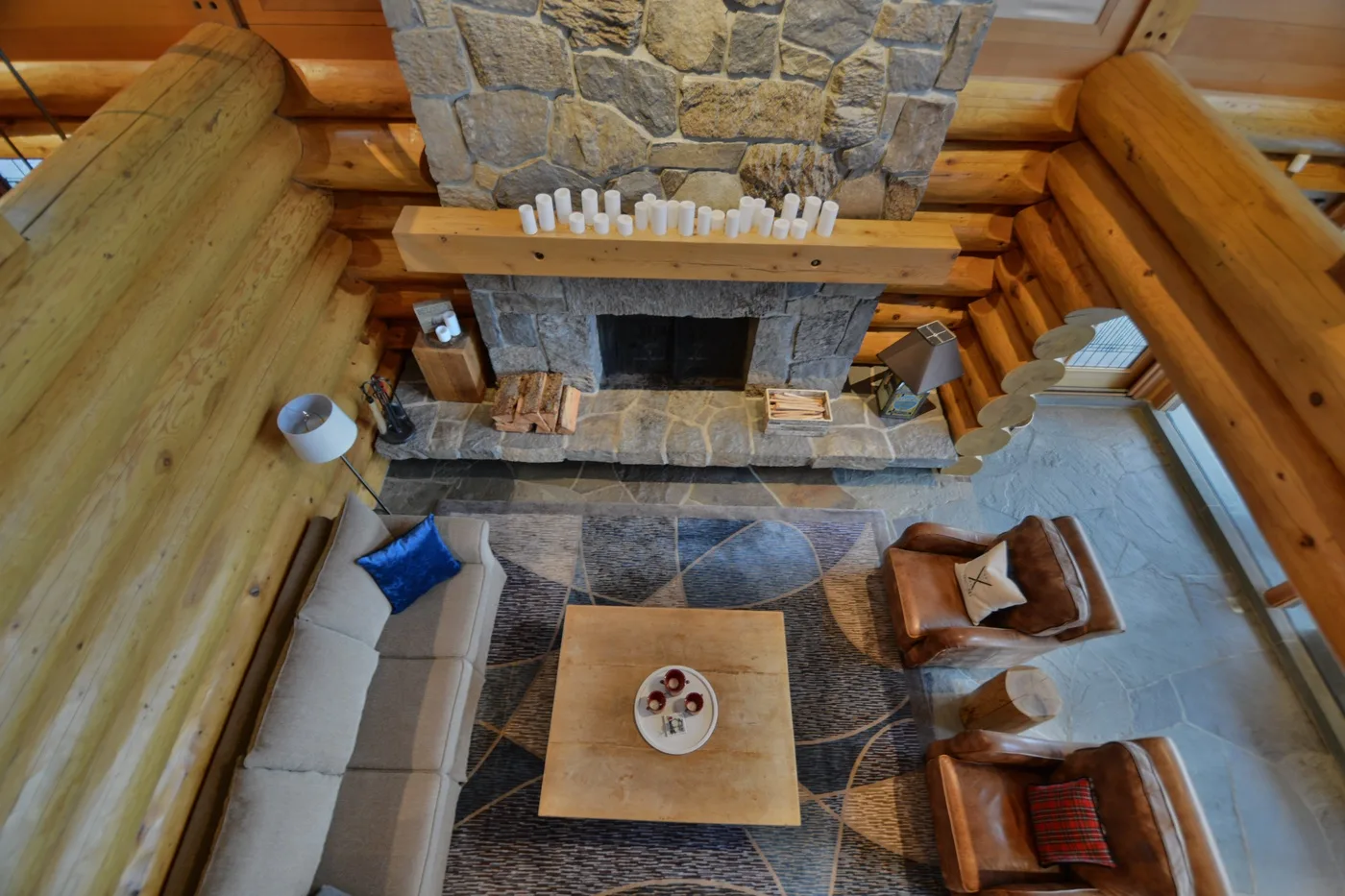 A log-cabin living room with a large stone fireplace and seating.