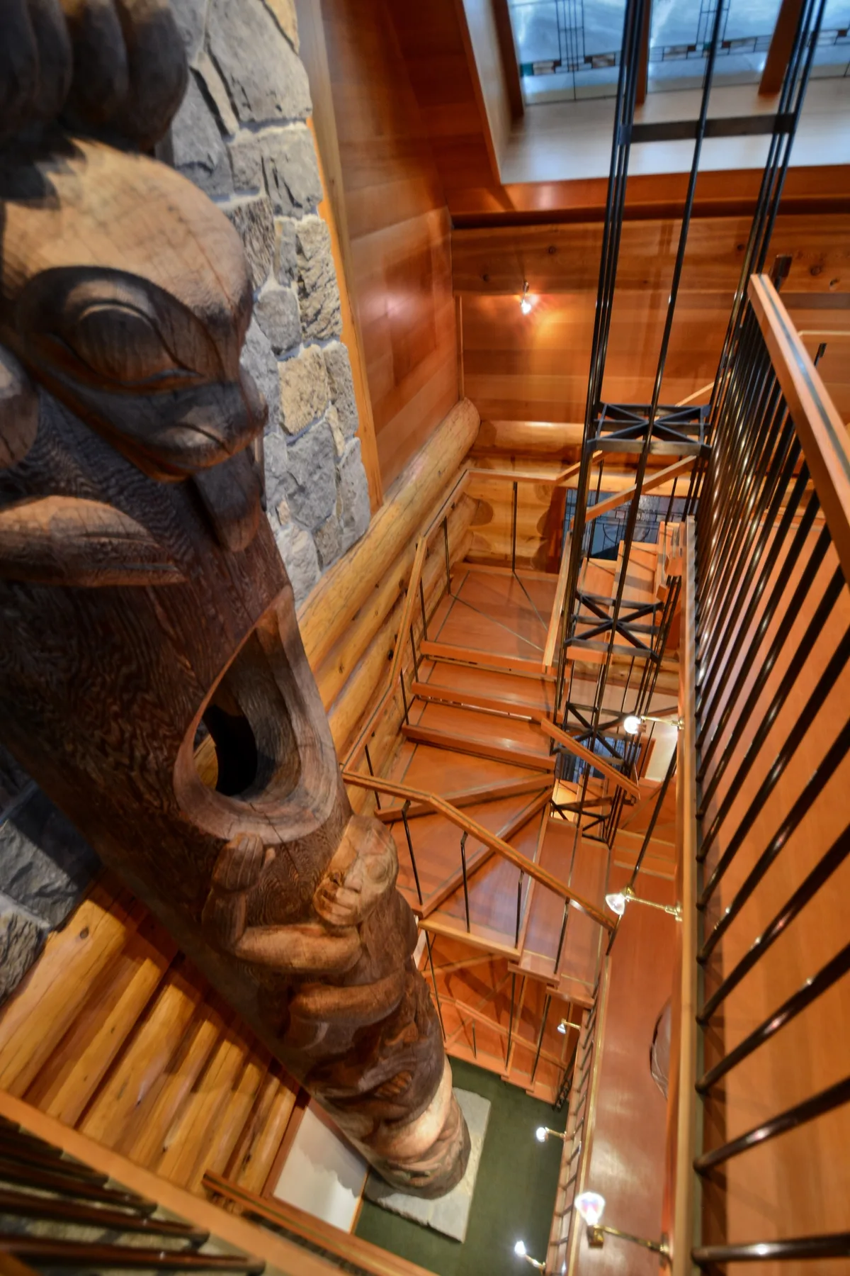 A wood-paneled interior stairwell with a carved wooden sculpture beside the stairs.