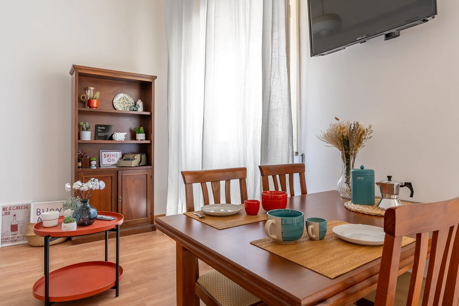 A dining area with a wooden table set with dishes beside a display cabinet.