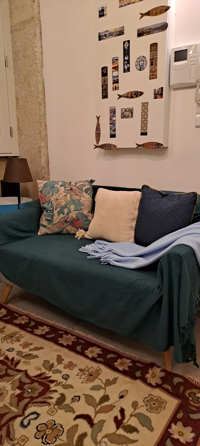 A living room with a teal seating area and a patterned rug.