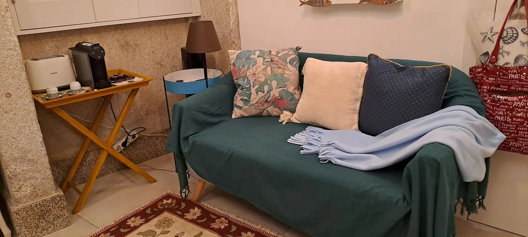 A living room with a teal sofa and a small side table.