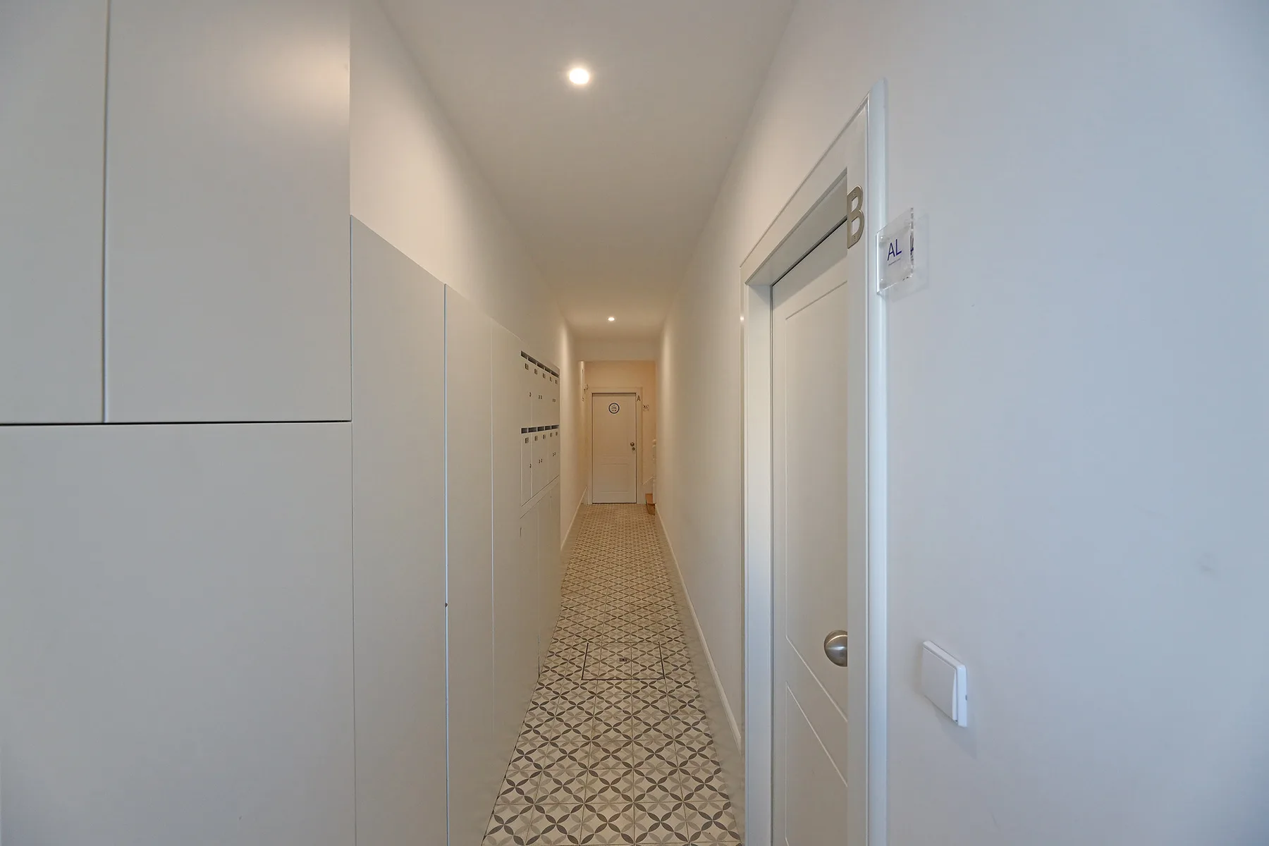 A narrow hallway with patterned tile flooring and several doors.